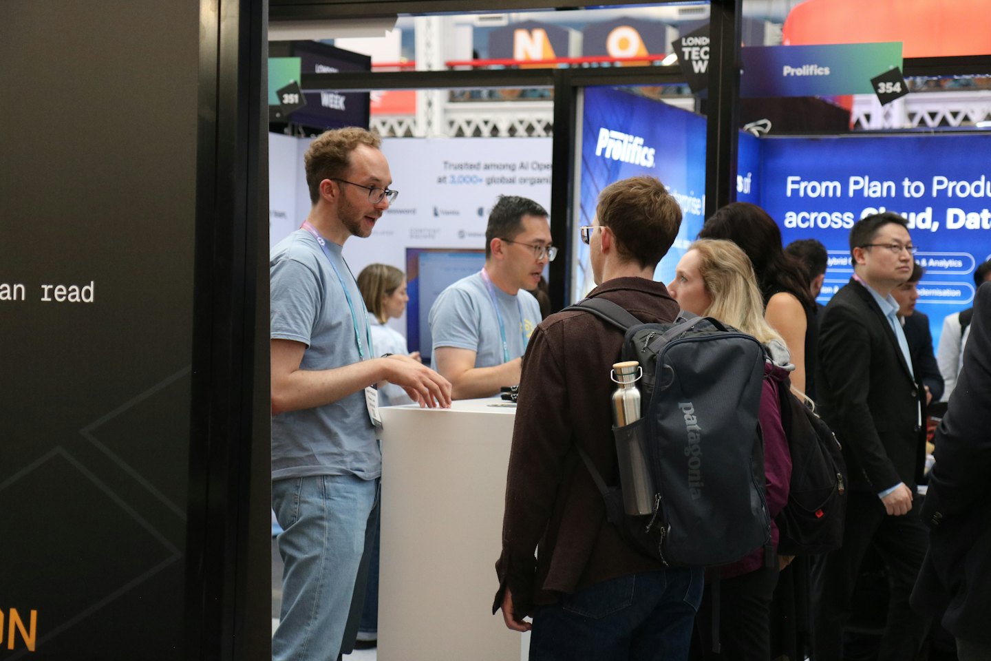 Professionals network and converse at a crowded trade show exhibition.