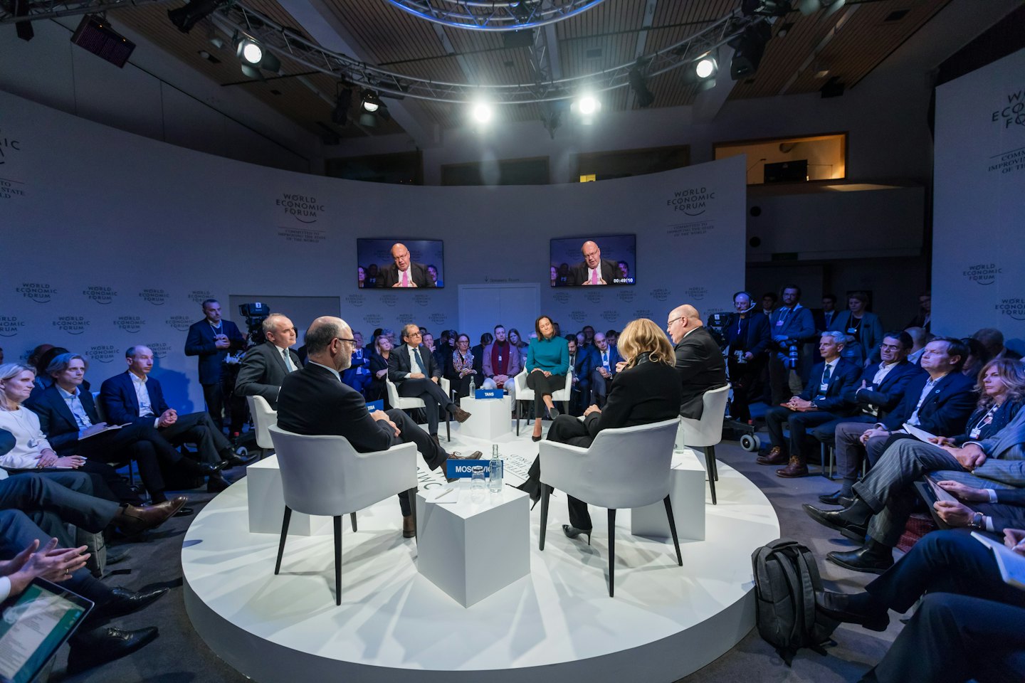 Business professionals on a circular stage at the World Economic Forum.