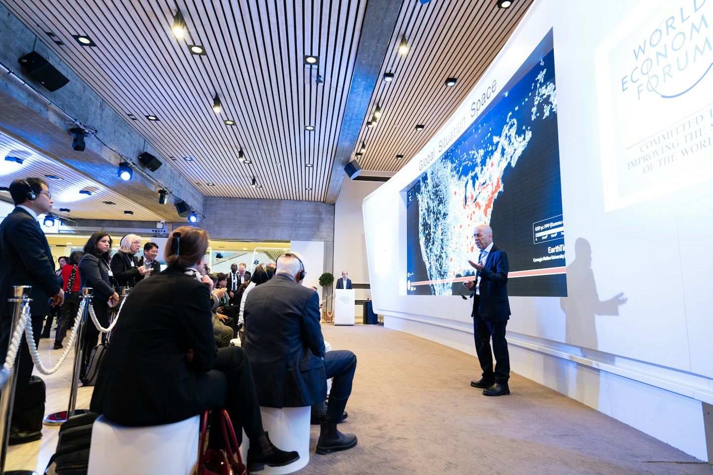 Man presents data map on curved screen to conference audience.