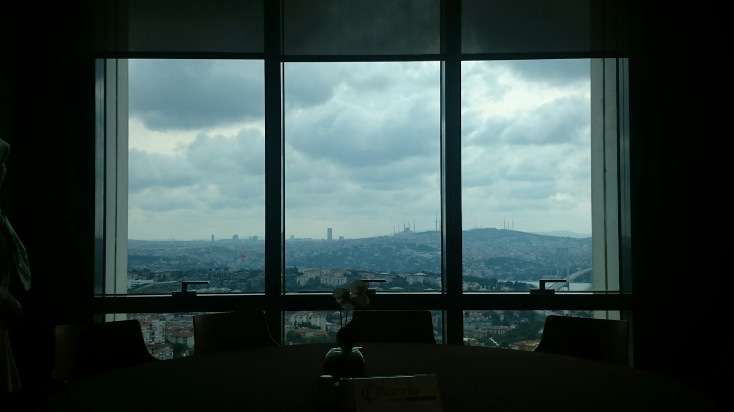 A person stands in a meeting room overlooking a city.